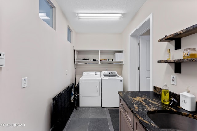 laundry room with washing machine and dryer, cabinets, sink, and a textured ceiling