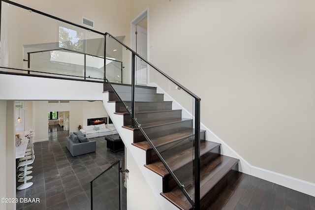 staircase with a towering ceiling, hardwood / wood-style floors, and plenty of natural light