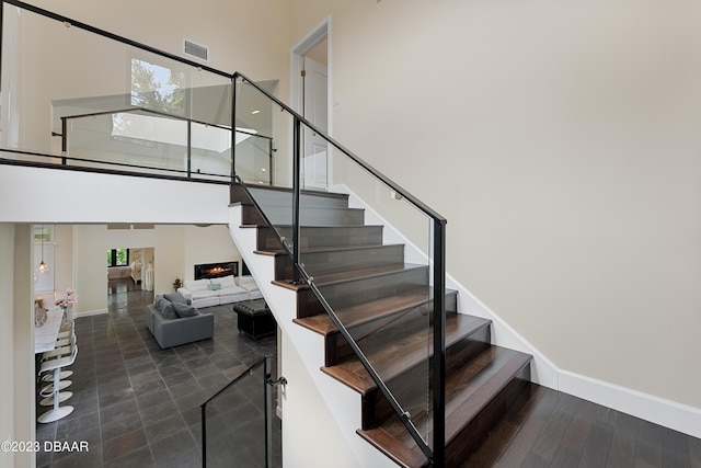 200 John Anderson Dr, Ormond Beach, FL 32176 - staircase with a high ceiling, a warm lit fireplace, and baseboards