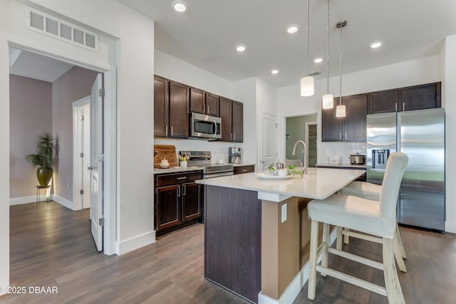 kitchen featuring visible vents, dark wood-type flooring, stainless steel appliances, dark brown cabinetry, and light countertops