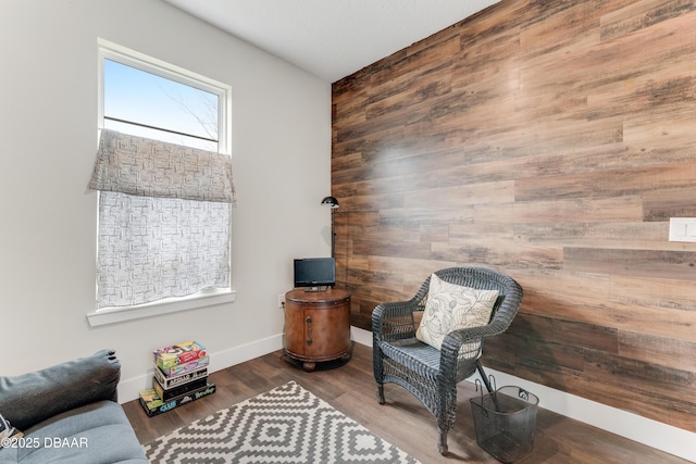 sitting room with wood walls, baseboards, and wood finished floors