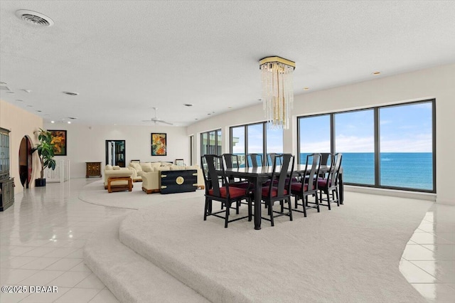 915 Ocean Shore Blvd Unit 801, Ormond Beach, FL 32176 - dining area with tile patterned floors, a textured ceiling, a water view, a ceiling fan, and a chandelier