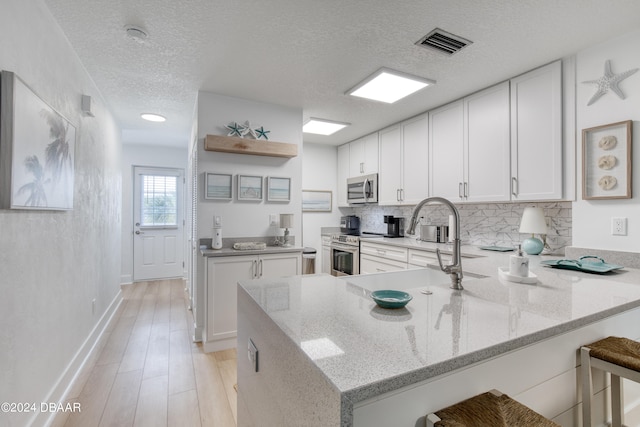 kitchen featuring white cabinets, kitchen peninsula, and stainless steel appliances