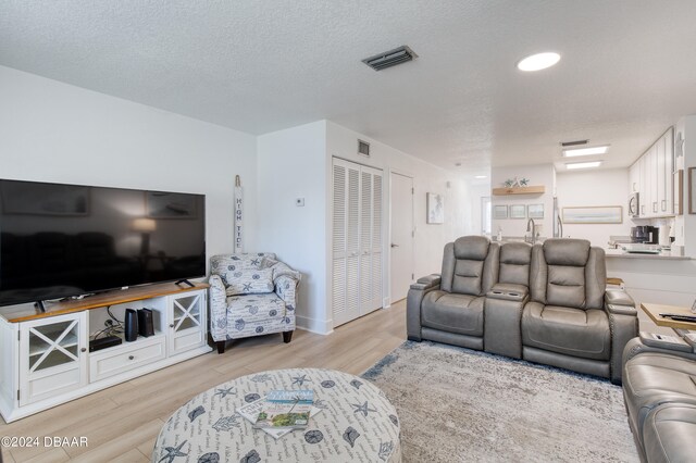 living room featuring a textured ceiling and light hardwood / wood-style flooring