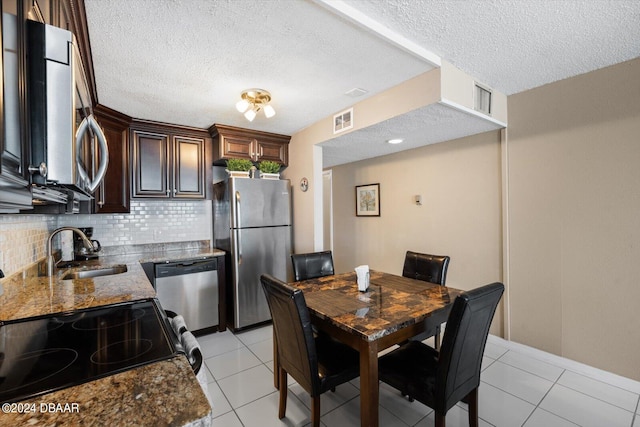 kitchen with stainless steel appliances, backsplash, a textured ceiling, stone counters, and sink