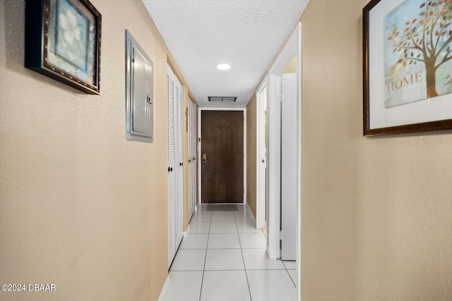 hallway featuring a textured ceiling, electric panel, and light tile patterned floors