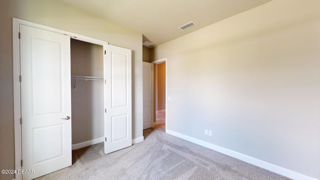 unfurnished bedroom with light carpet and a closet