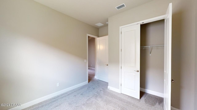 unfurnished bedroom with a closet and light colored carpet