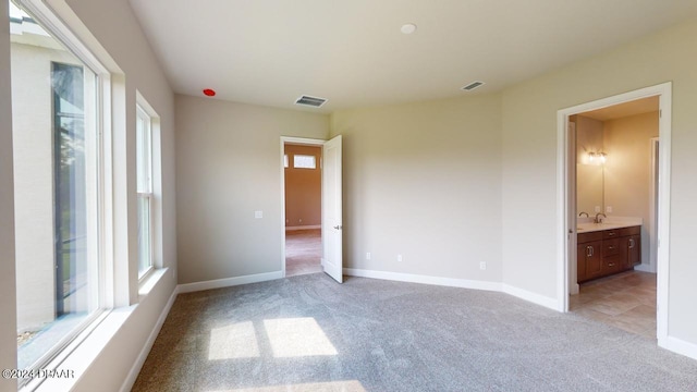 unfurnished bedroom featuring ensuite bathroom and light colored carpet