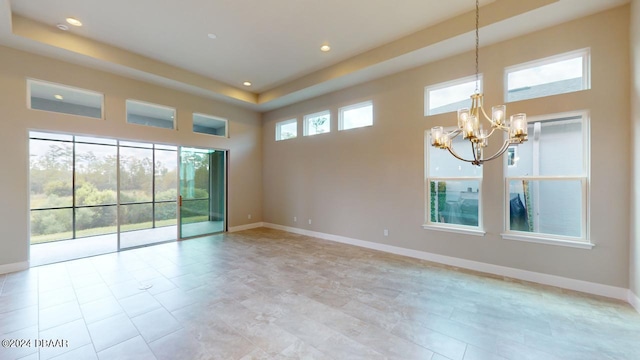 tiled empty room featuring a towering ceiling and a chandelier