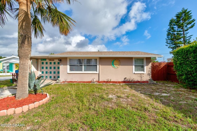 view of front of property featuring an attached garage, fence, and a front lawn