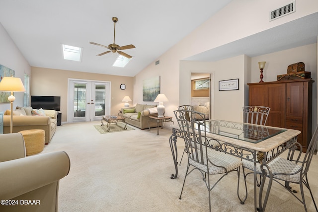 carpeted dining area with lofted ceiling with skylight, french doors, and ceiling fan