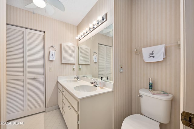 bathroom featuring toilet, vanity, and ceiling fan