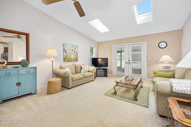 carpeted living room featuring french doors, ceiling fan, and lofted ceiling with skylight