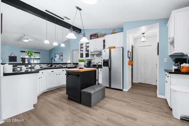 kitchen featuring a kitchen island, tasteful backsplash, lofted ceiling, white cabinets, and appliances with stainless steel finishes