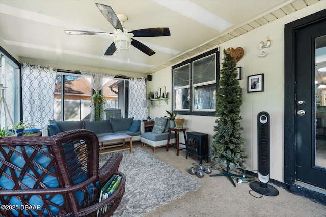 sunroom / solarium featuring a wood stove and ceiling fan