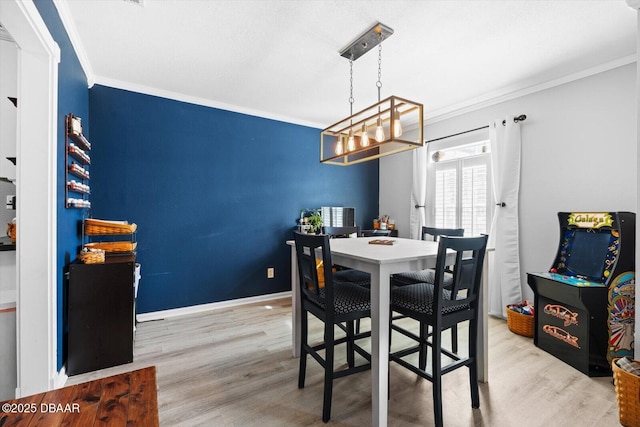 dining room with crown molding, light hardwood / wood-style floors, and an inviting chandelier