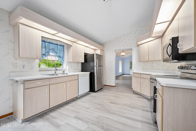 kitchen with sink, appliances with stainless steel finishes, light brown cabinetry, light hardwood / wood-style flooring, and lofted ceiling