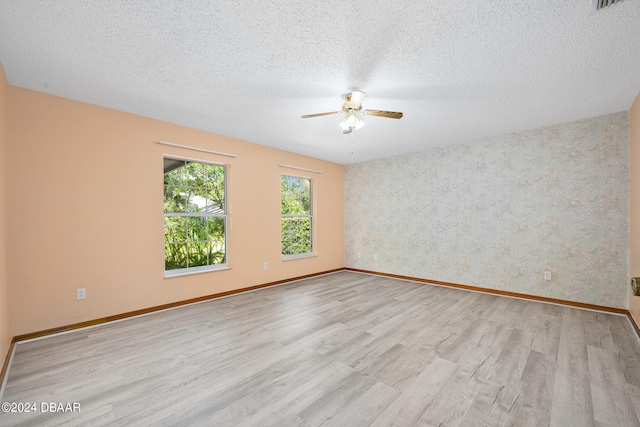 unfurnished room with light hardwood / wood-style floors, ceiling fan, and a textured ceiling