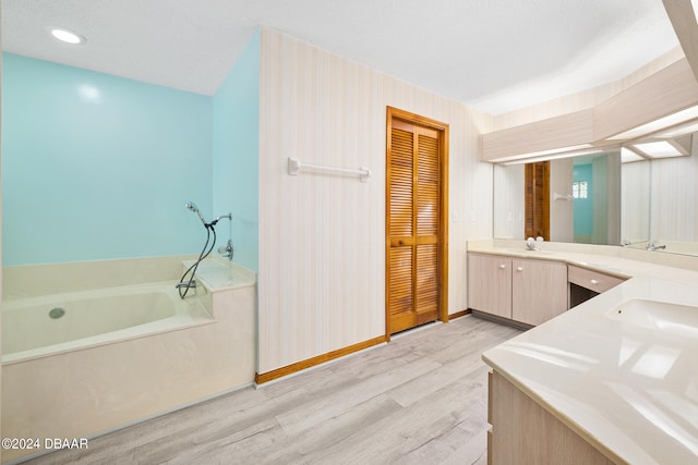 bathroom with a bathing tub, wood-type flooring, a textured ceiling, and vanity