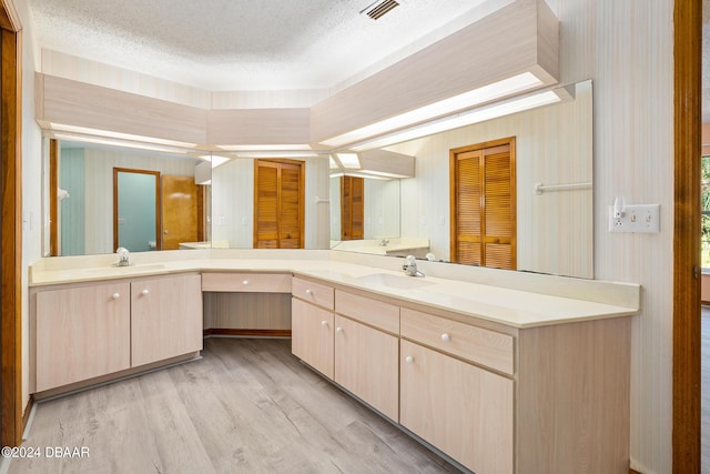 212 Glenbriar Cir, Daytona Beach, FL 32114 - bathroom with wood finished floors, a textured ceiling, vanity, and wallpapered walls