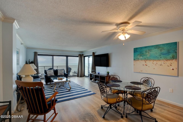 dining space featuring ceiling fan, crown molding, a textured ceiling, and light wood-type flooring