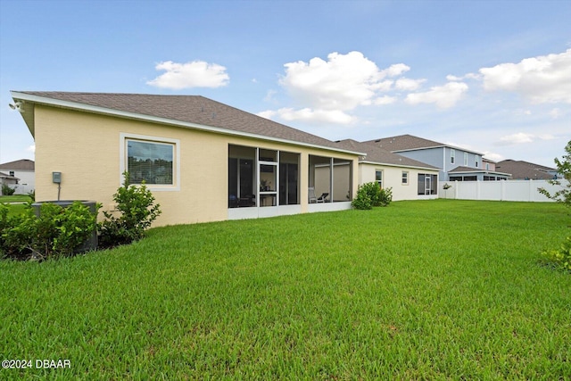 rear view of property featuring a sunroom and a lawn