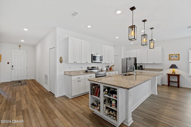 kitchen featuring a center island with sink, light hardwood / wood-style flooring, light stone countertops, white cabinetry, and appliances with stainless steel finishes