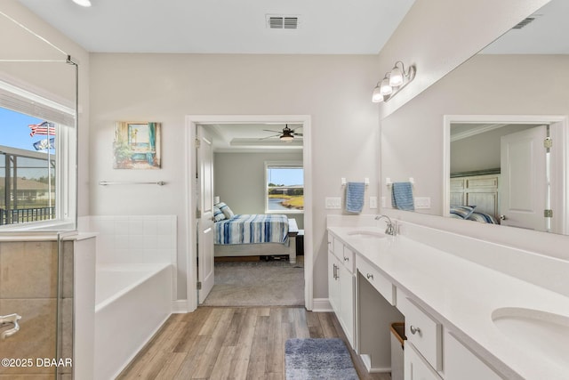 ensuite bathroom featuring a healthy amount of sunlight, ensuite bath, visible vents, and wood finished floors