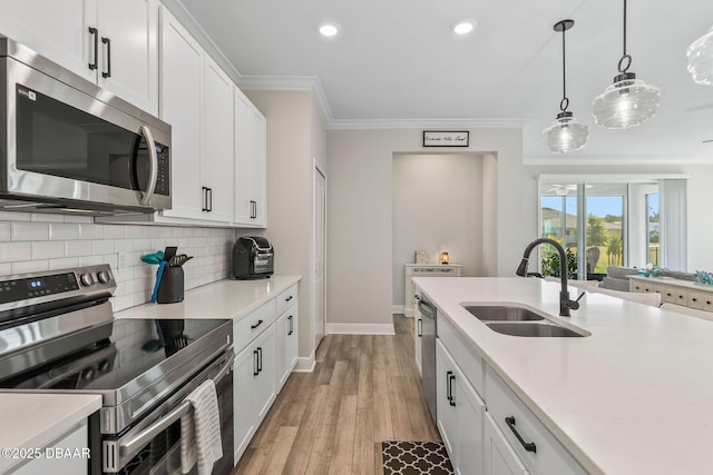 kitchen featuring a sink, stainless steel appliances, decorative backsplash, ornamental molding, and recessed lighting