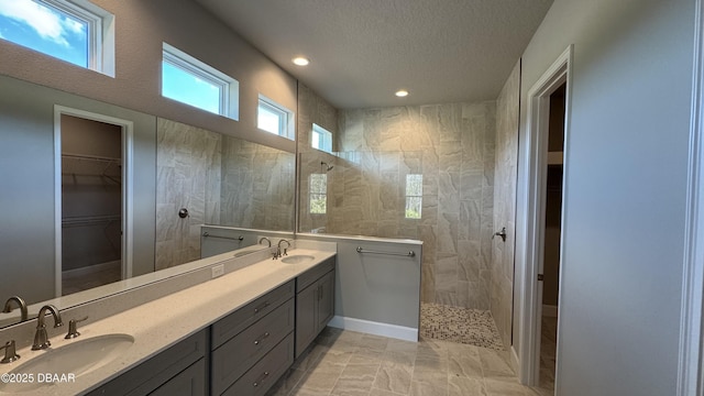 bathroom with a tile shower, tile patterned flooring, vanity, and a textured ceiling