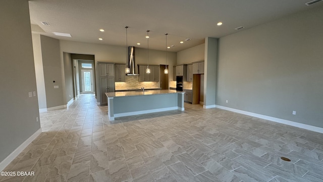 kitchen featuring gray cabinets, a center island, pendant lighting, and wall chimney range hood