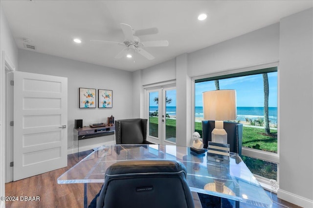 home office with ceiling fan, wood-type flooring, and a water view