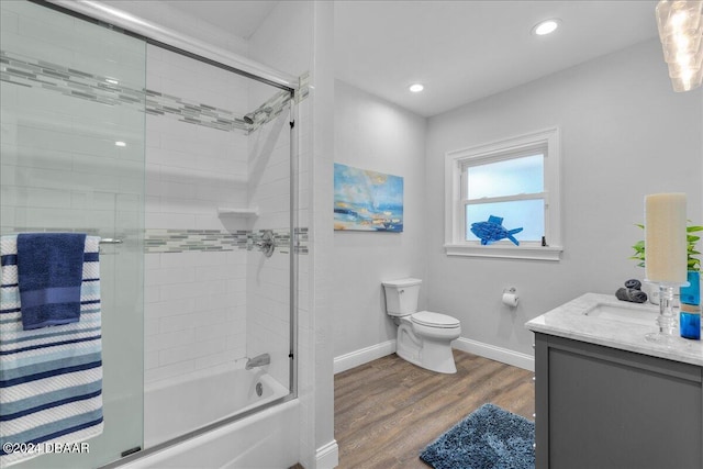 full bathroom featuring shower / bath combination with glass door, hardwood / wood-style flooring, toilet, and vanity