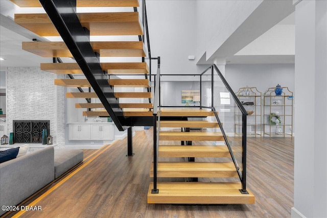 stairway with a fireplace and wood-type flooring