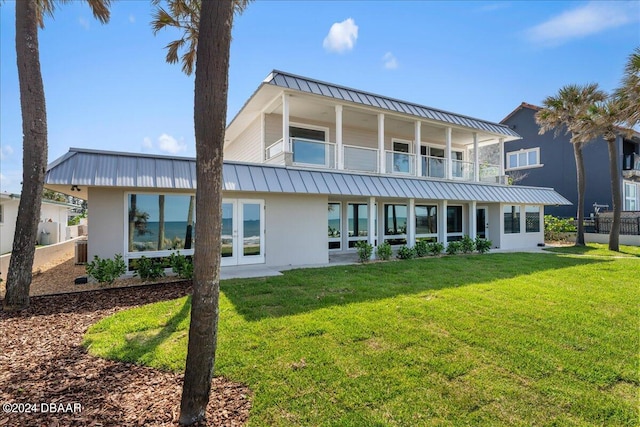 rear view of house featuring central air condition unit, a lawn, and a balcony