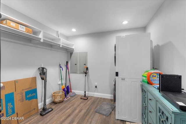 washroom featuring hardwood / wood-style flooring and stacked washer / dryer