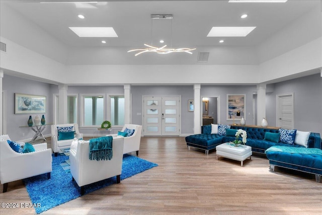 living room featuring light hardwood / wood-style floors, a chandelier, and a high ceiling