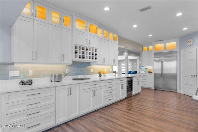 kitchen featuring stainless steel built in fridge, beverage cooler, white cabinets, dark wood-type flooring, and decorative backsplash