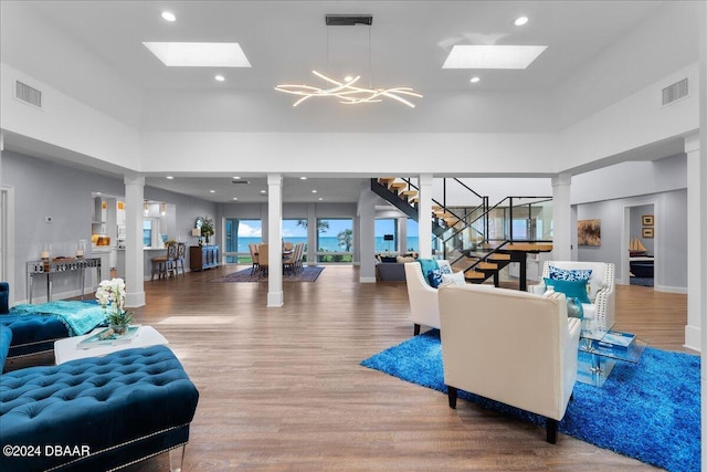 717 Ocean Shore Blvd, Ormond Beach, FL 32176 - living area with a skylight, wood finished floors, stairway, ornate columns, and a towering ceiling