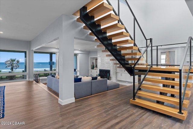 stairway with a fireplace, a water view, and hardwood / wood-style flooring