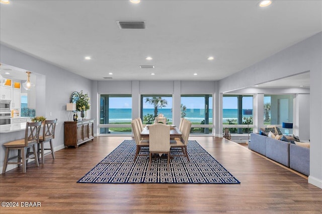 dining room featuring dark hardwood / wood-style flooring and a water view