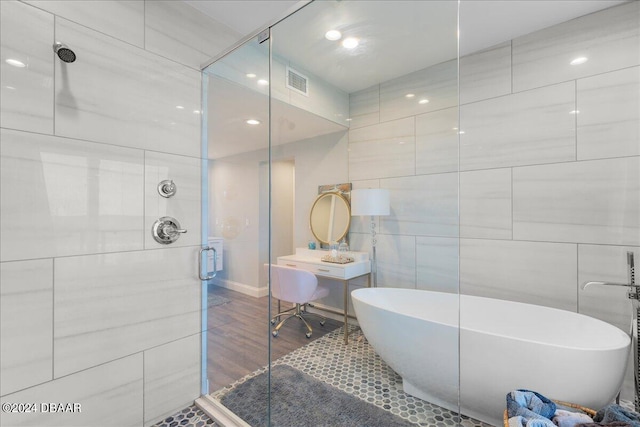 bathroom with hardwood / wood-style flooring, independent shower and bath, and tile walls