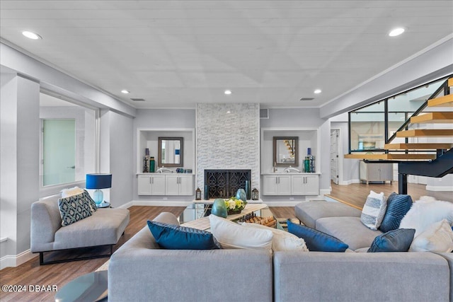 living room featuring a stone fireplace, hardwood / wood-style floors, and crown molding