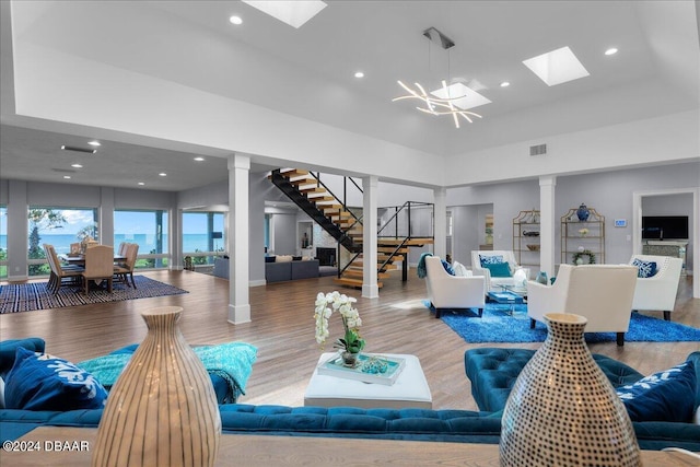 living room with an inviting chandelier, a tray ceiling, and wood-type flooring