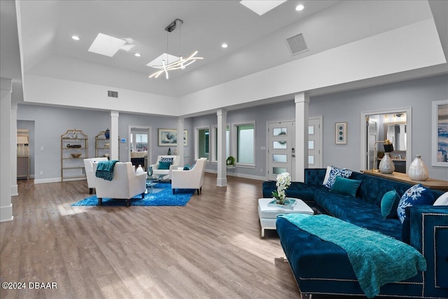 living room with a high ceiling, a tray ceiling, and light hardwood / wood-style flooring