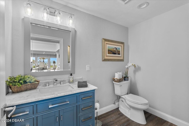 bathroom with toilet, vanity, and wood-type flooring