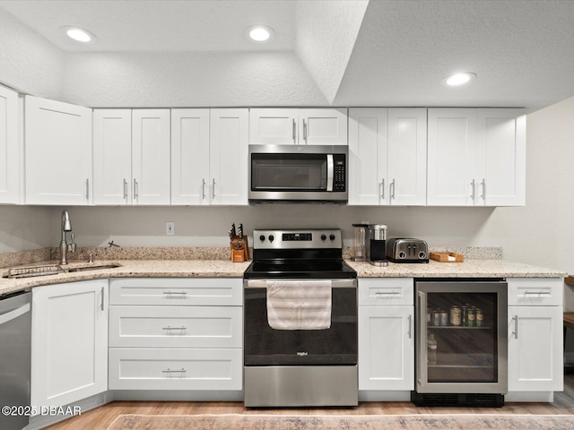 4795 S Atlantic Ave Unit 15, Ponce Inlet, FL 32127 - kitchen with stainless steel appliances, wine cooler, white cabinets, recessed lighting, and a textured ceiling