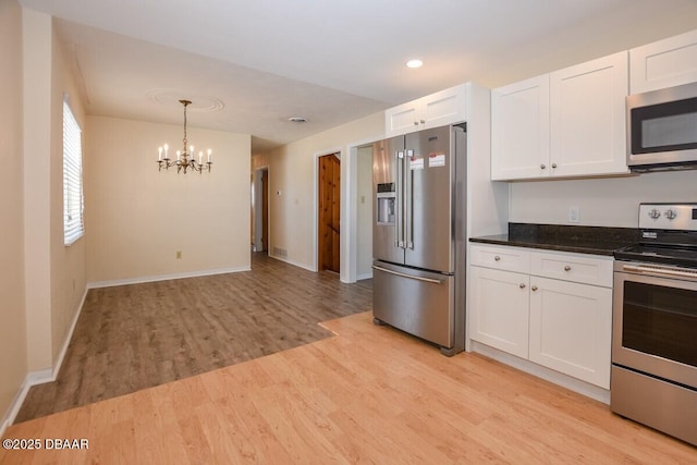 kitchen featuring stainless steel appliances, white cabinets, light hardwood / wood-style floors, and decorative light fixtures