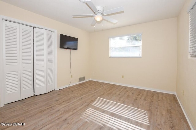 unfurnished bedroom featuring ceiling fan, light hardwood / wood-style floors, and a closet